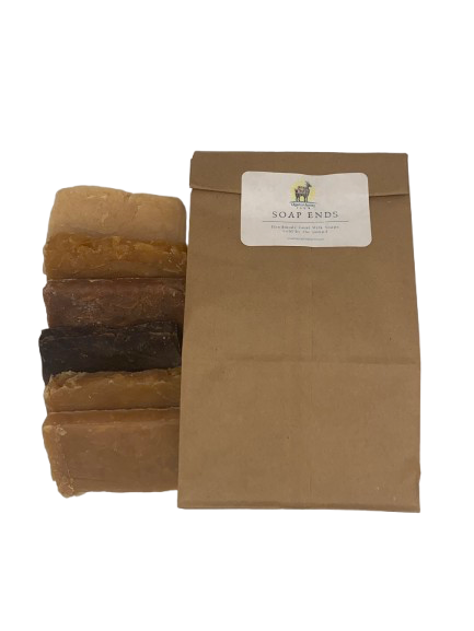 Three bars of soap stacked next to a brown paper bag with 'Soap Ends' branding on a white background.